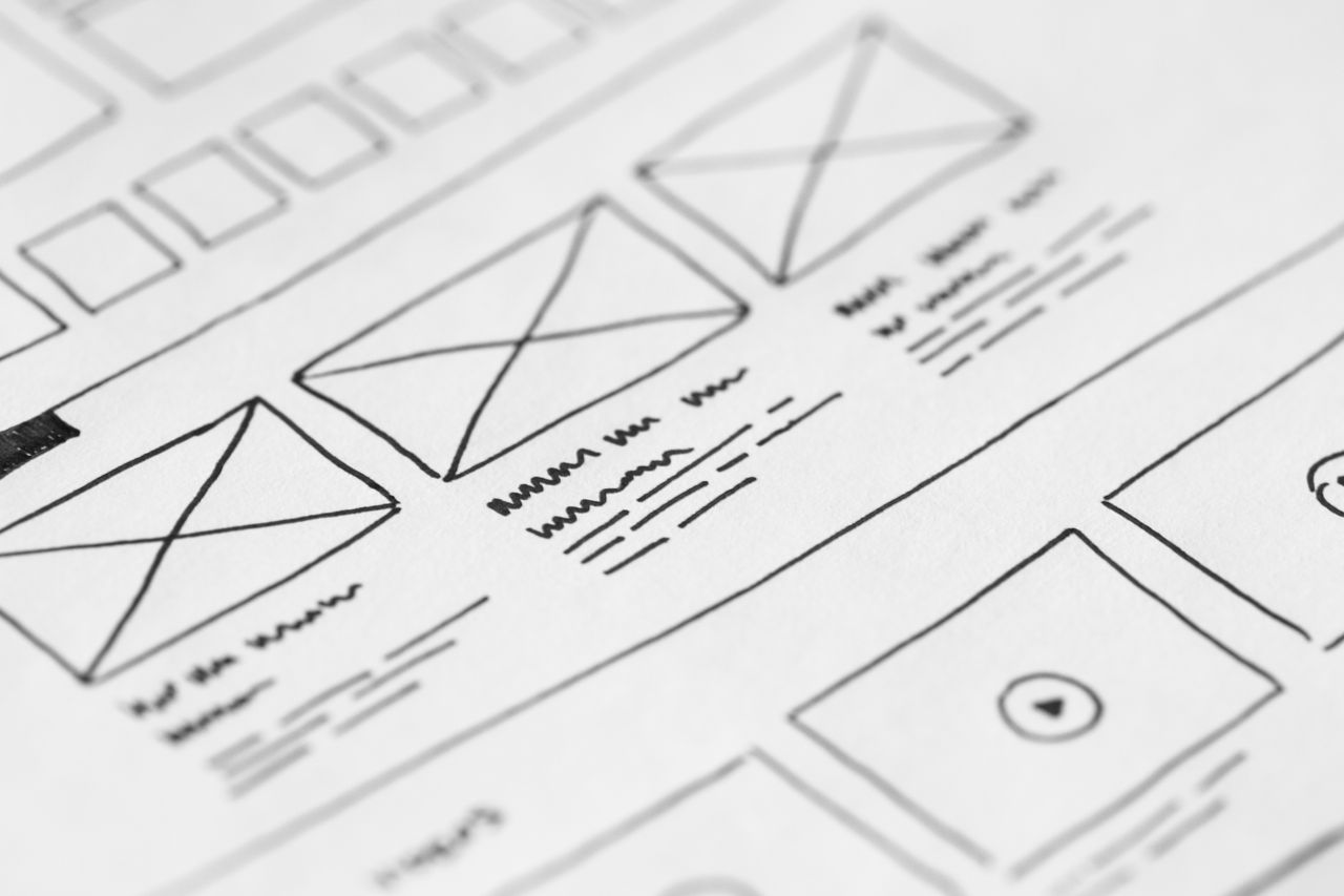 A detailed close-up of a hand-sketched wireframe on paper for a UX project.